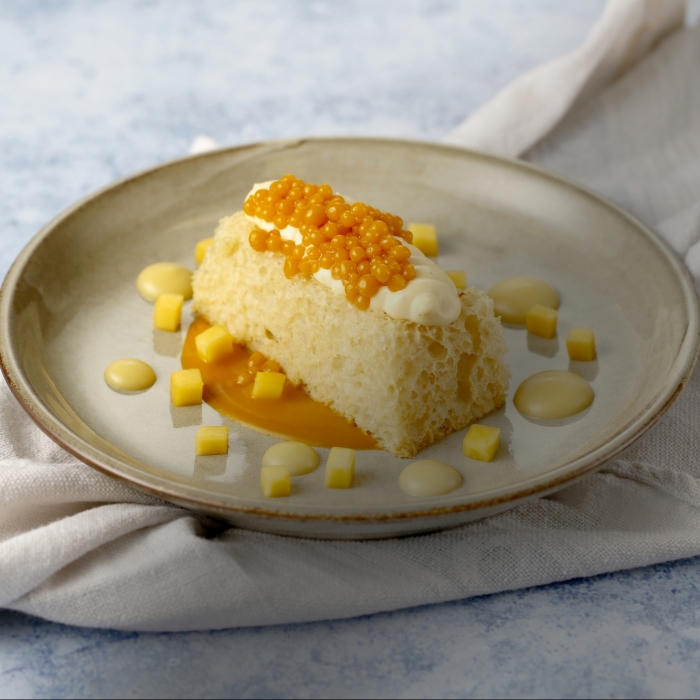 Mango sponge with clotted custard, served with a passion fruit emulsion and mango caviar
